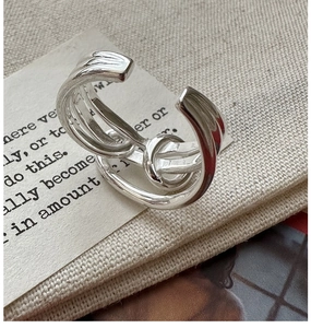 Detailed macro view of S925 sterling silver multi-layer knotted wrap ring on fabric