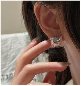 Macro shot of silver geometric square stud earrings with shimmering textured finish