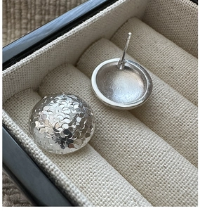 Macro detail of S925 sterling silver stud earrings with textured hammer finish surface