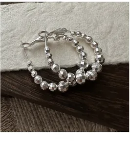 Détail de boucles d'oreilles créoles en argent S925 avec perles à facettes disco