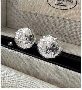Macro shot of silver round earrings with hammered texture on linen jewelry box padding