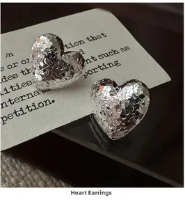 Detailed view of silver heart earrings featuring a unique hammered metal texture finish
