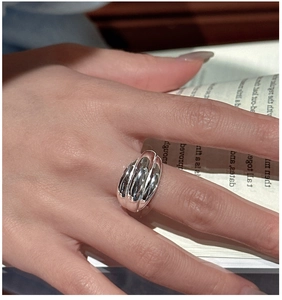Dettaglio dell'anello d'argento a coste larghe indossato sulla mano con sfondo libro