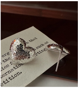 Close-up of S925 sterling silver heart earrings with a unique hammered metal texture