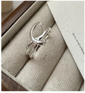 Detailansicht des S925 Silberknotenrings auf einer eleganten Tweed-Schmuckschatulle