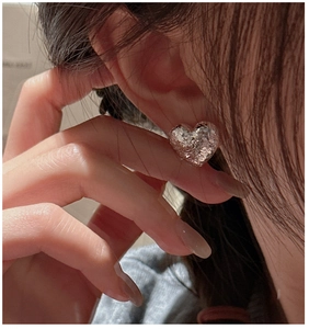 Macro shot of S925 sterling silver heart earrings with sparkling textured finish on ear