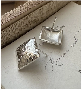 Macro shot of silver square stud earrings featuring a delicate hammered metal texture