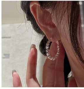 Détail de créoles en argent sterling S925 avec perles laser facettées sur l'oreille