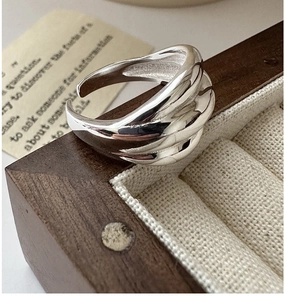 Dettaglio macro anello in argento sterling S925 ritorto su portagioie in legno scuro