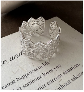 Macro shot of silver open ring with intricate lace texture and geometric cutout details