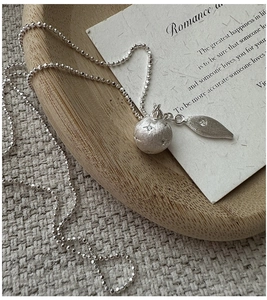 Detail of S925 silver ball necklace featuring matte star engraving and zircon leaf charm