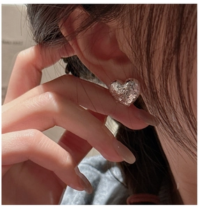 Detailed macro view of S925 silver heart stud earrings with crushed ice glitter texture