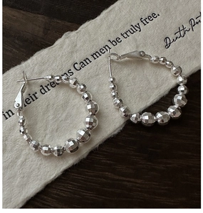 Détail macro de créoles en argent sterling S925 avec perles facettées et éclat métallique