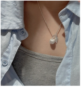 Detail view of S925 sterling silver ball and leaf pendant on model with beaded chain