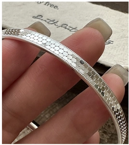 Macro detail of 925 sterling silver bangle showing honeycomb texture and embossed edges