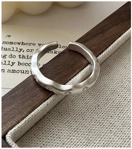 Détail macro d'une bague vague en argent S925 avec texture mate et accents pointillés