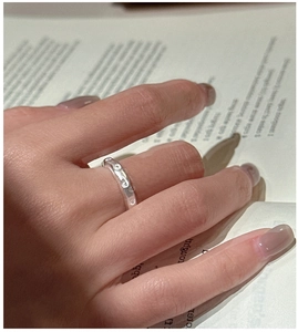 Gros plan d'une bague en argent à texture martelée sur un fond de magazine de mode