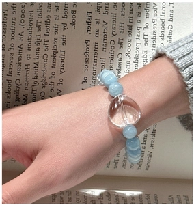 Détail d'un bracelet en perles d'aigue-marine avec grand pendentif cœur porté au poignet