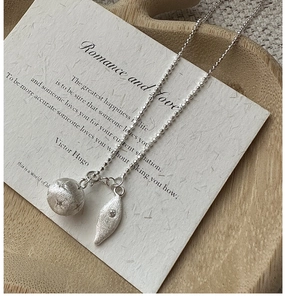 Detail of S925 silver necklace featuring a brushed star-etched bead and leaf pendant
