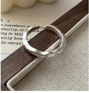 Détail macro d'une bague S925 en argent sterling avec texture mate et design ondulé