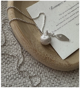 Detail of S925 silver beaded necklace with star-engraved orb and gem-set leaf pendant