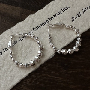 Créoles chic en argent S925 avec perles à facettes laser sur un fond minimaliste