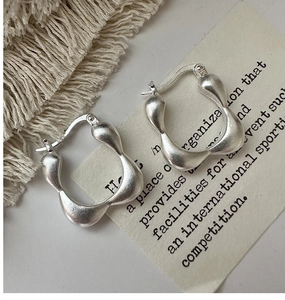 Detailed view of matte S925 sterling silver square hoop earrings on a beige display card