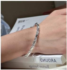 Detail of S925 sterling silver zircon bracelet on model with elegant book background