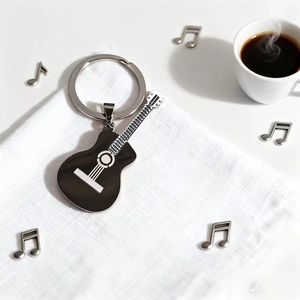 Polished black stainless steel guitar keychain with silver strings on a white fabric