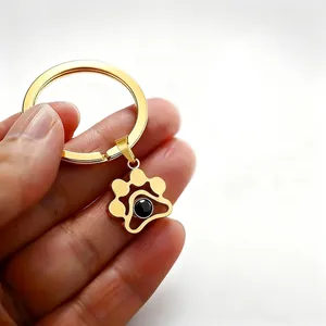 Detailed view of a gold cat paw keychain with a 100 languages I love you projection stone