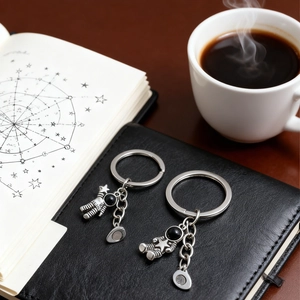 Detail of silver astronaut keychains with magnetic clasp on a black leather notebook