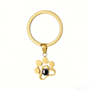 Detail of gold metal cat paw keychain with black projection bead and mirror finish