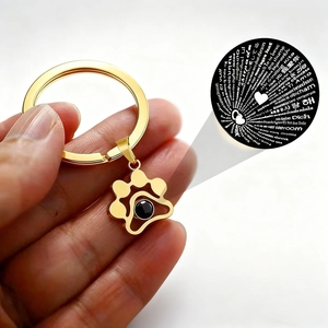 Gold pet paw projection keychain featuring 100 languages of I Love You on white background