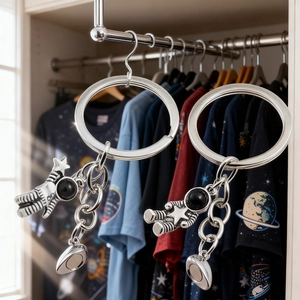 Macro detail of silver magnetic astronaut and planet keychains hanging on a metal rod