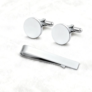Polished silver stainless steel cufflink and tie clip set for men on white plush fabric