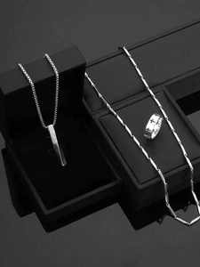 Macro detail of men's stainless steel cross ring and geometric necklaces set in black box
