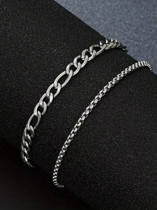 Polished silver Figaro and Box chain bracelet set displayed on a sleek black column stand