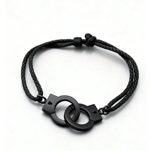 Black leather cord bracelet with metal handcuffs charms on a clean white background
