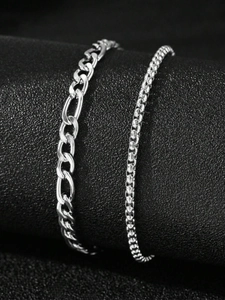 Detailed close-up of Figaro and round bead stainless steel bracelets on black leather display