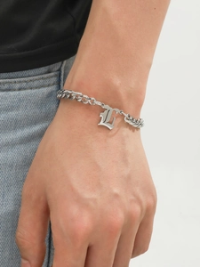 Close-up of a silver Cuban chain bracelet featuring a polished Gothic letter L pendant