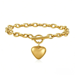 Détail d'un bracelet doré à maillons épais avec fermoir à bascule et pendentif cœur