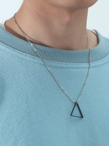 Gros plan d'un collier pendentif triangle noir mat sur un sweat à capuche bleu