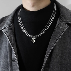 Gros plan d'un collier chaîne cubaine double couche avec pendentif lettre G gothique