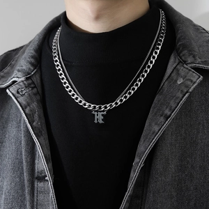 Détail d'un collier homme double couche maille cubaine avec pendentif lettre 'HF' en argent