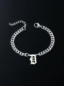Macro detail of silver stainless steel Cuban chain bracelet with Gothic D letter pendant