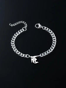 Detailed close-up of a silver cuban link bracelet with a gothic letter pendant on black surface