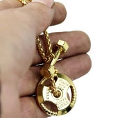 Close-up of golden fitness necklace with 20KG weight plate and dumbbell charms
