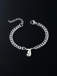 Macro detail of silver stainless steel curb chain bracelet with gothic letter J pendant