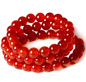 Macro detail of three stacked red agate bead bracelets with polished finish and glossy texture