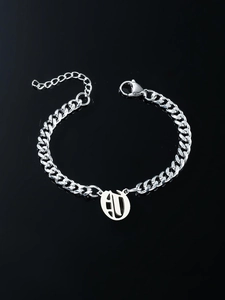 Detail view of silver Cuban link bracelet with engraved oval alphabet letter pendant